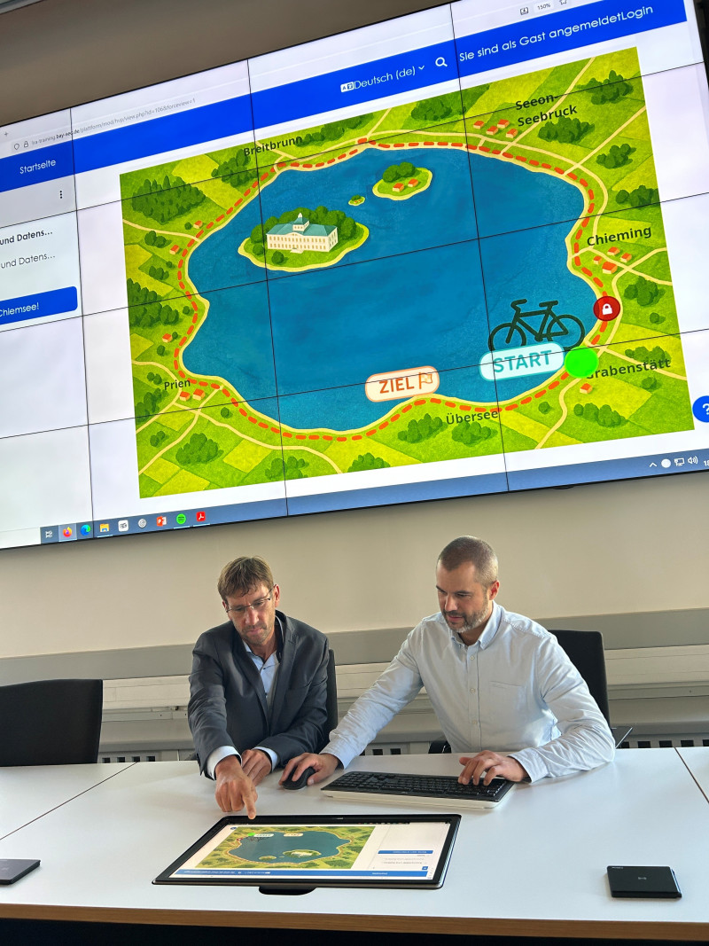 Claus Hofmann (Informationssicherheitsbeauftragter, links) und Andreas Klimm (Projektmanagement Office, rechts) präsentieren das neue Lernspiel „Radltour um den Chiemsee“ zur Cybersicherheit. ©Landratsamt Traunstein